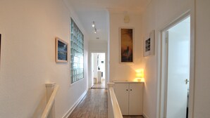 A narrow hallway with wooden flooring, white walls, and a white door at the end. - Ard na Mara- Coastal Apartment (Pittenweem)