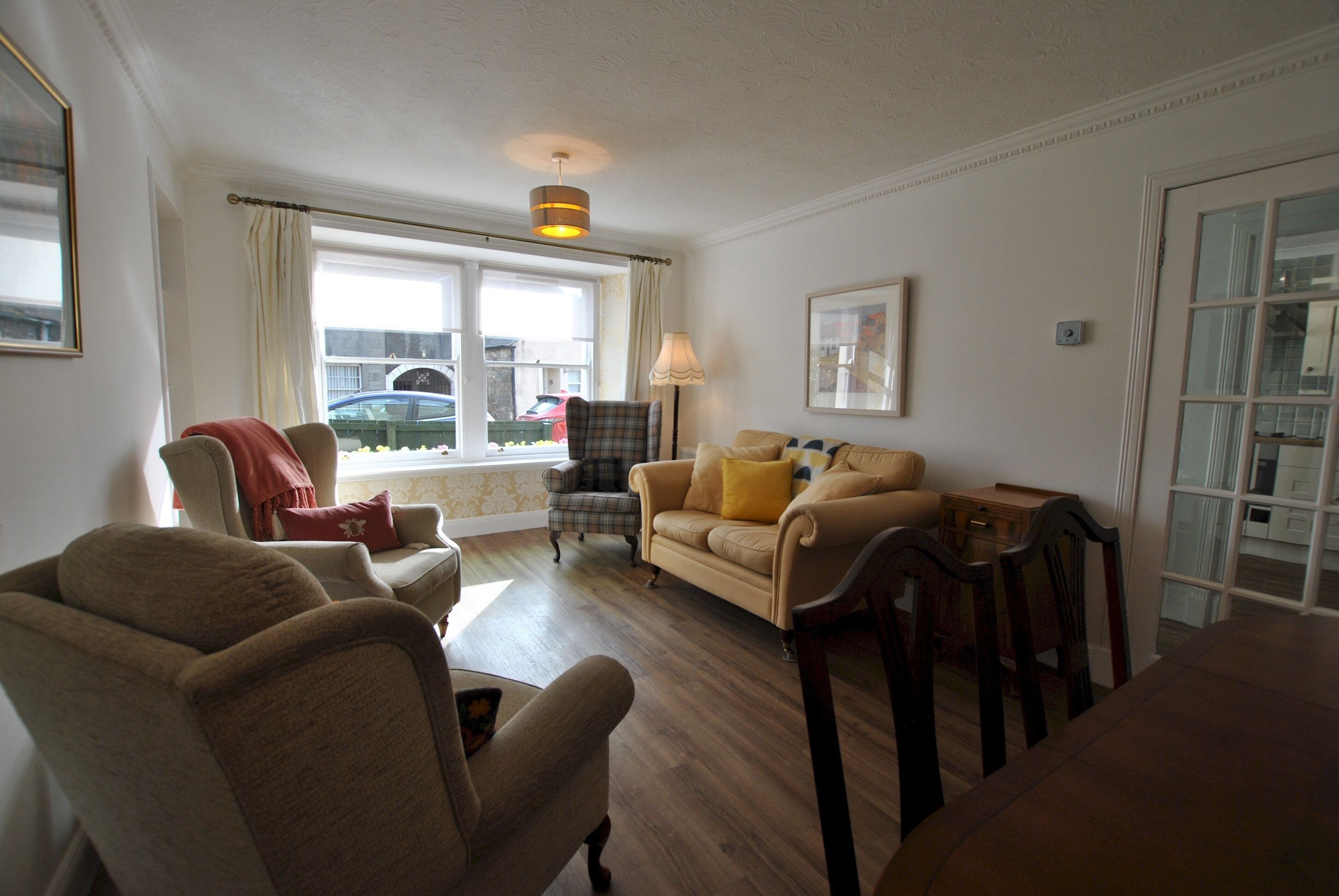 A living room with a sofa, armchairs, a table, and a lamp.