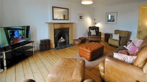 A living room with a fireplace, leather furniture, and a television.