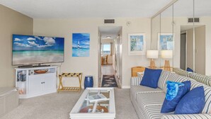 A living room with a TV, a sofa, a coffee table, and artwork on the walls.