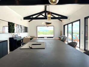 Cozinha moderna com uma ilha grande, um piano e vista para o exterior.