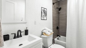 A modern bathroom with a white sink, black faucet, and a toilet with a basket of white towels. - Charming 2-bedroom apartment in dowtown Decatur/ 20 min from downtown ATL (Decatur)