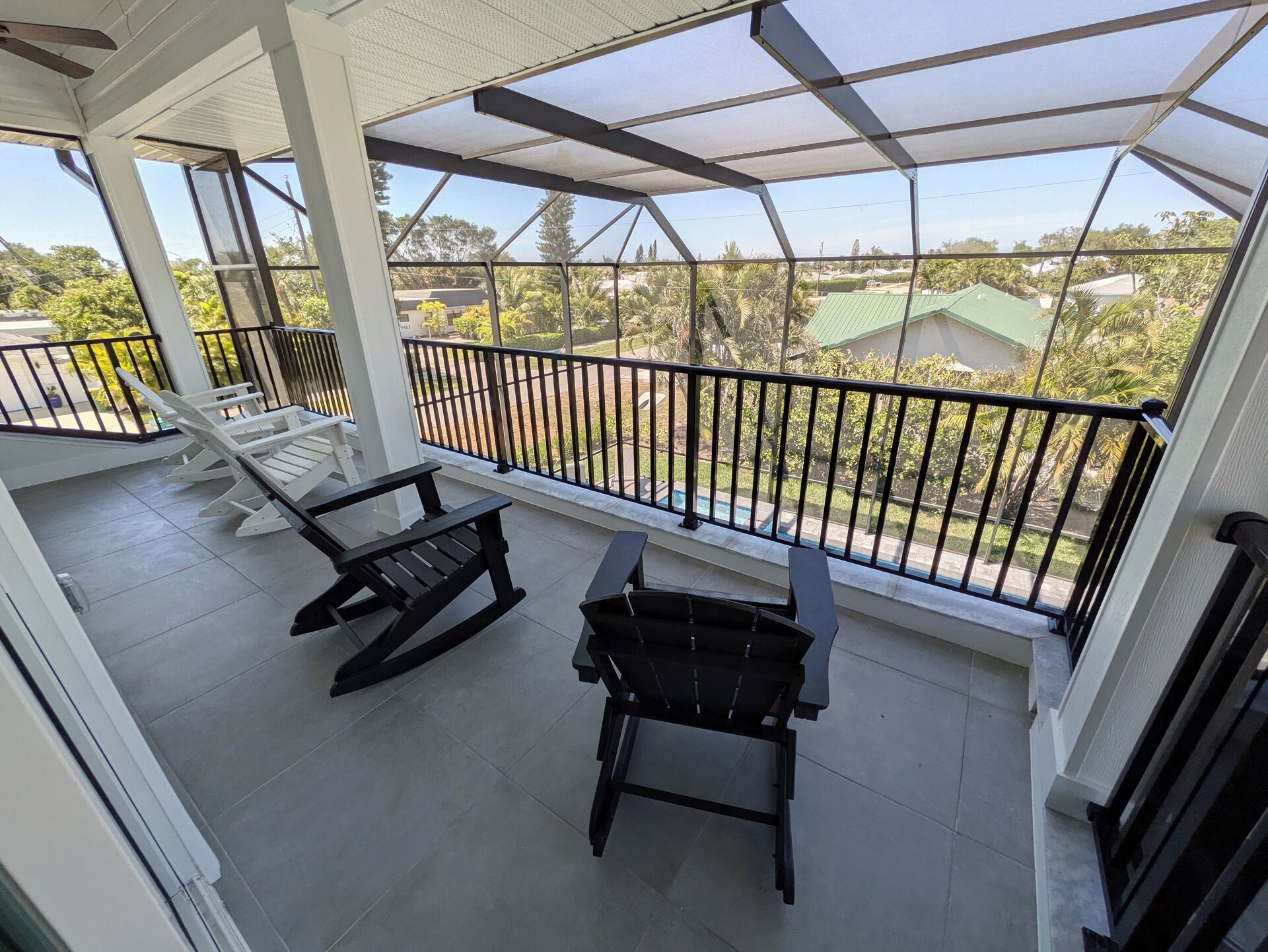 A covered balcony with two rocking chairs and a view of a residential area.