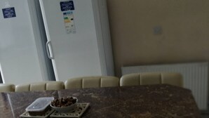 A kitchen area with a marble countertop, a white refrigerator, and a beige chair.