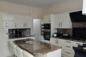 A modern kitchen with white cabinets, a marble countertop, a built-in oven, and a microwave. - Room-charming Bradford Room to Rent With (Bradford)