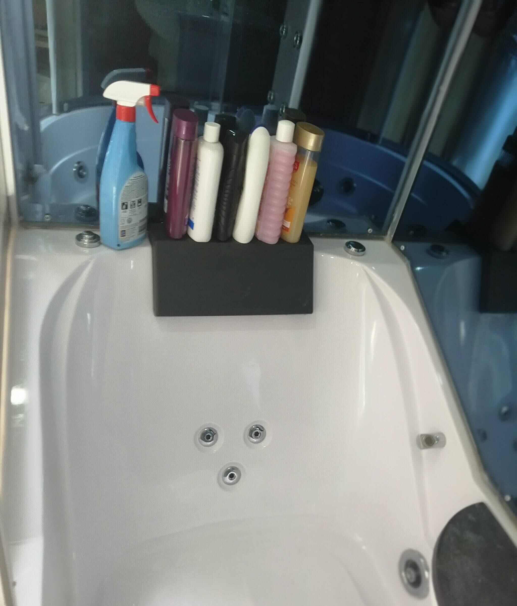 A bathtub with a black tray holding various toiletries.