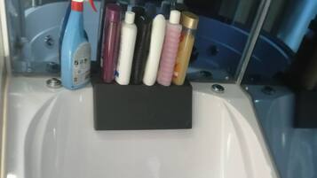 A bathtub with a black tray holding various toiletries.
