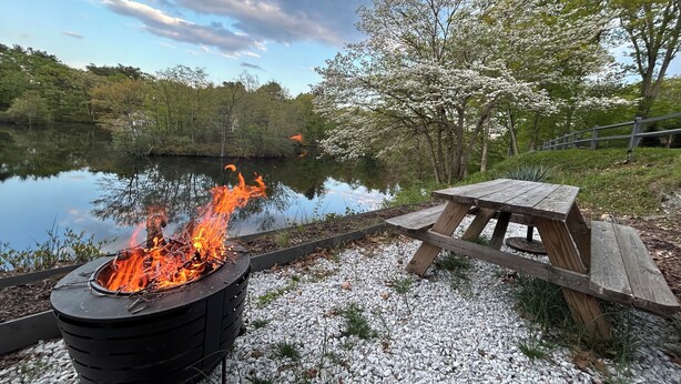 A campfire with a wooden table and benches by a lake. - 2BR, 2 King beds, 1 BA, and Kitchenette in Lakeside Home in Greenwich. (Greenwich)