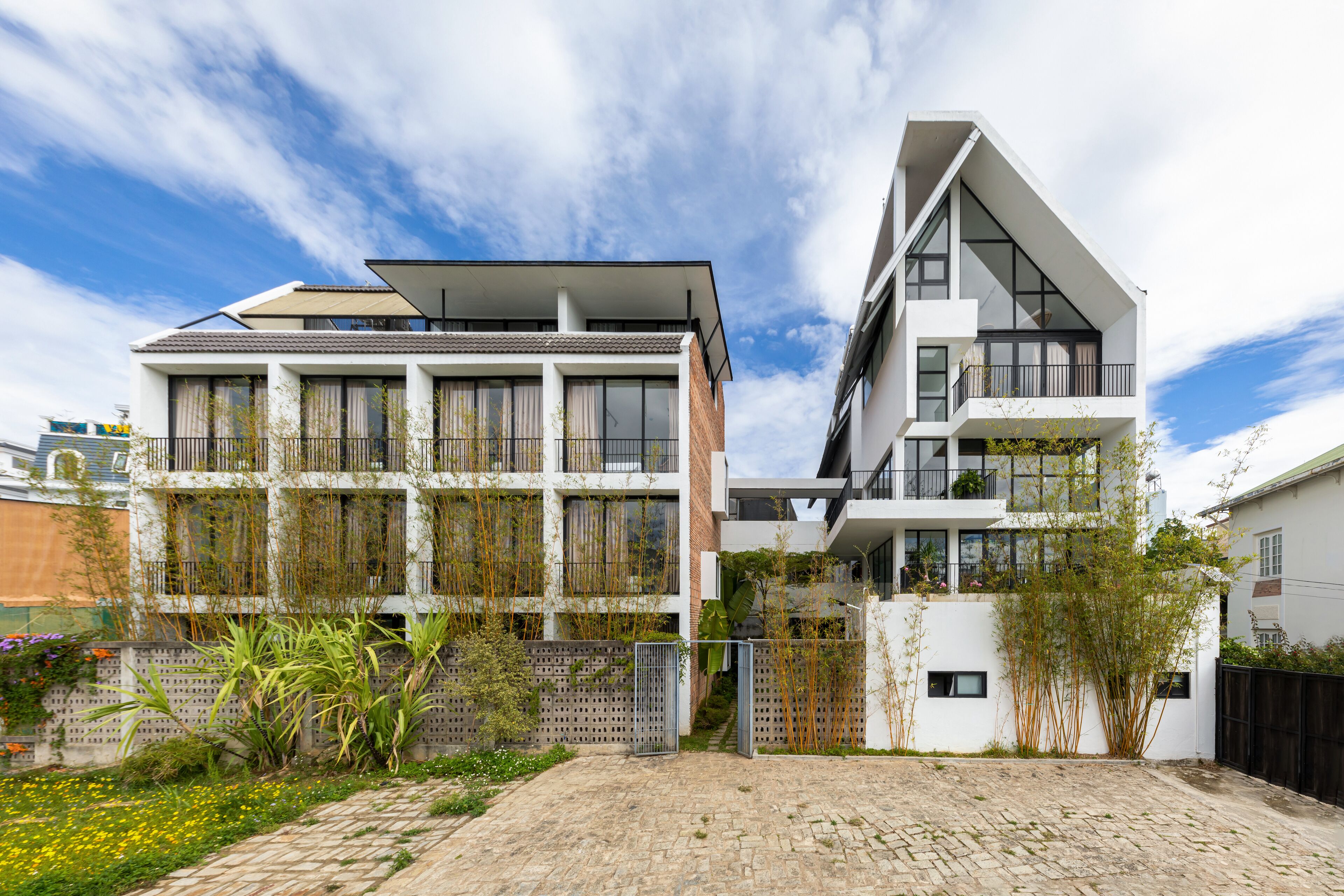 A modern two-story residential building with a flat roof, large windows, and a balcony.
