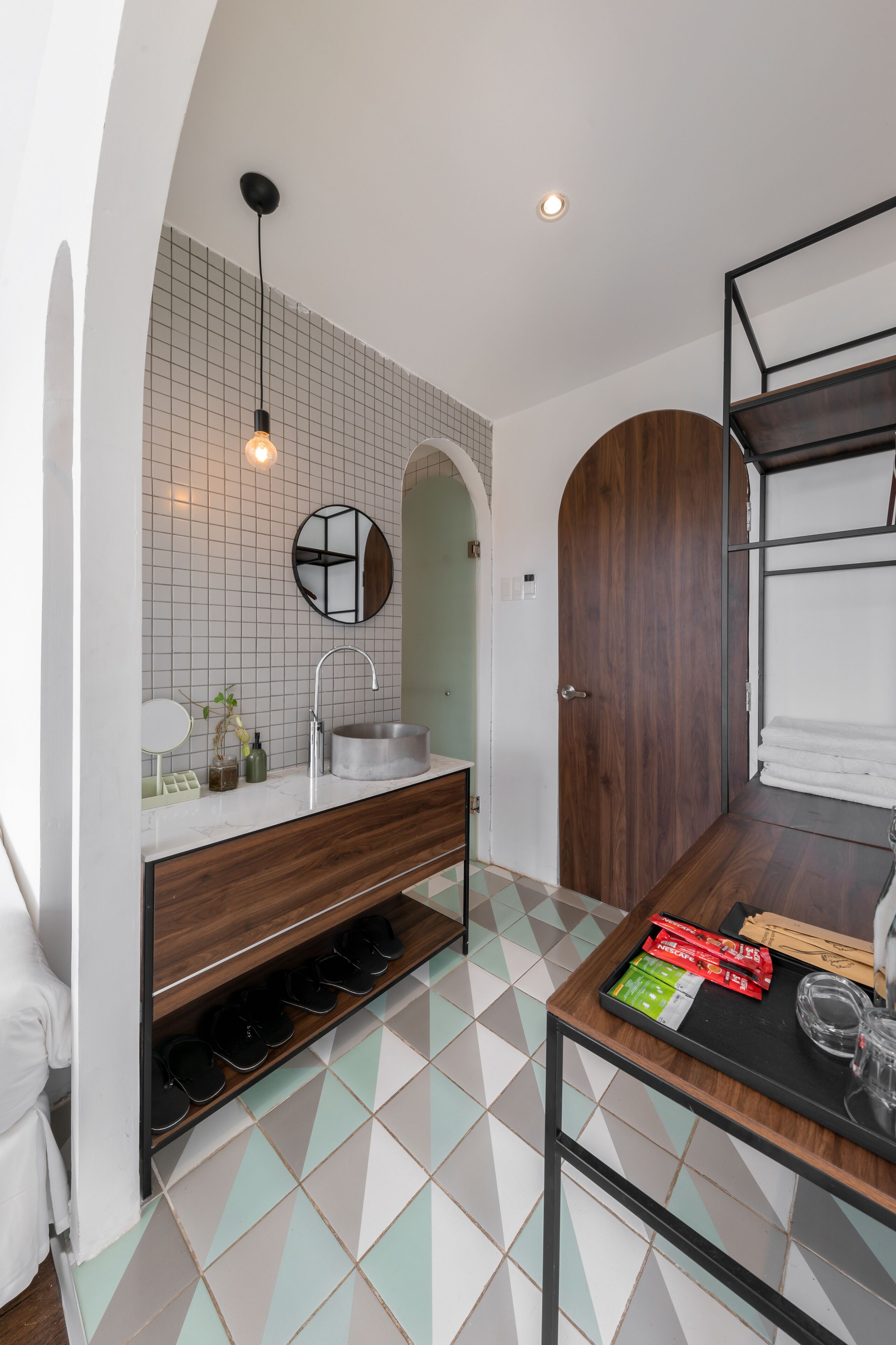 A modern bathroom with a sink, mirror, and towel rack.