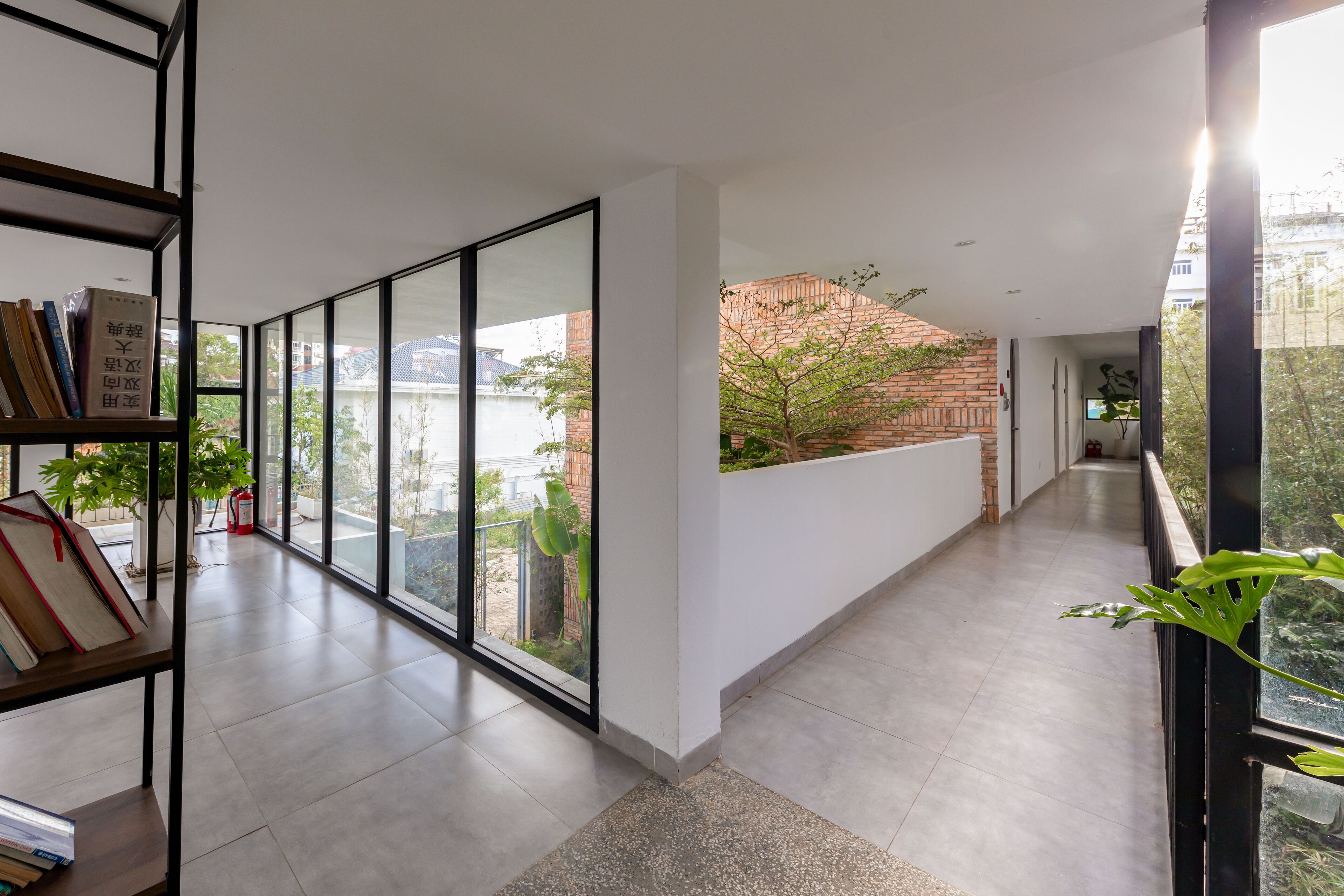 A modern interior with a long corridor, large windows, and a brick wall outside.