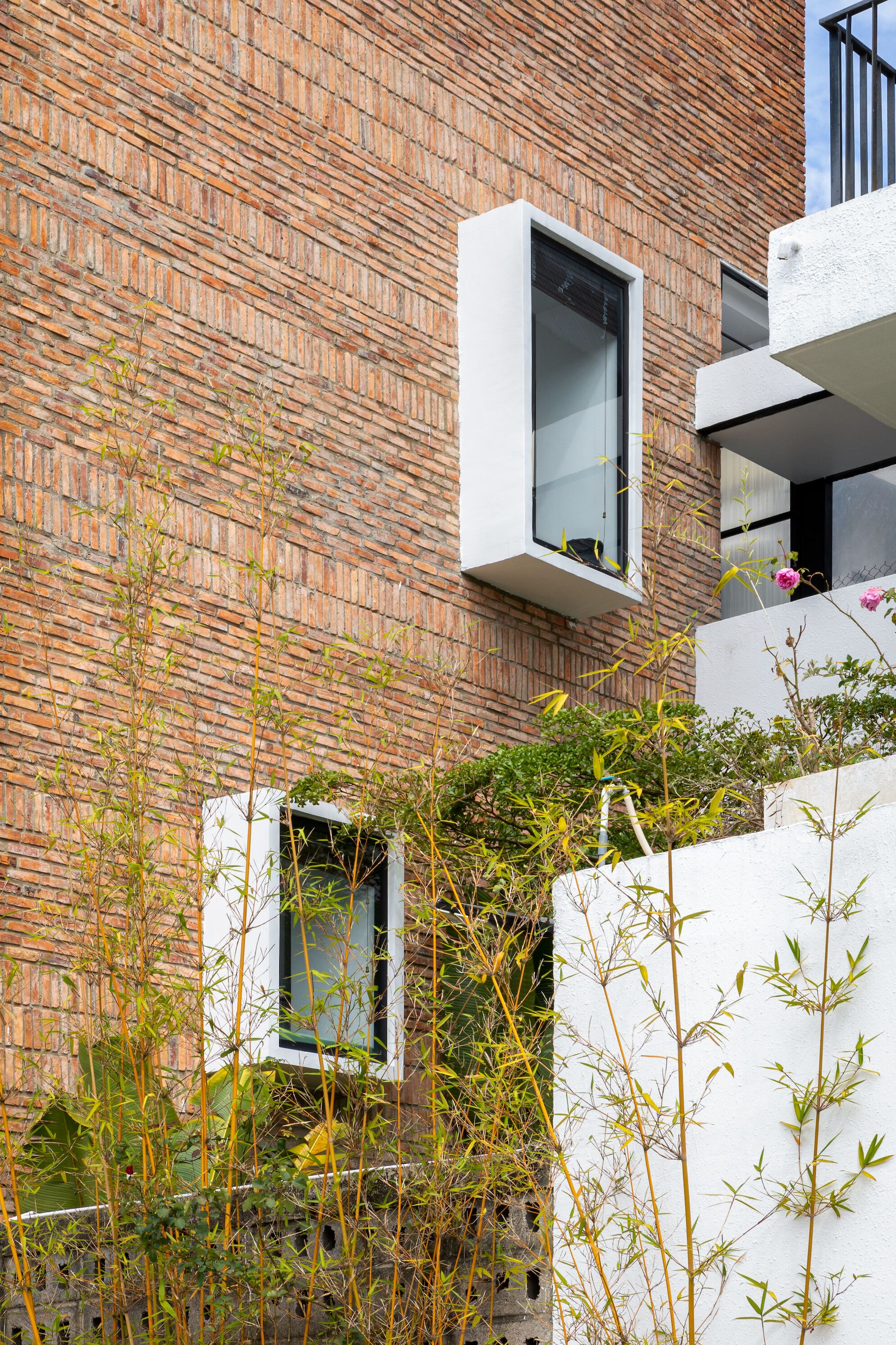 A modern building with a brick facade, white balconies, and small windows.