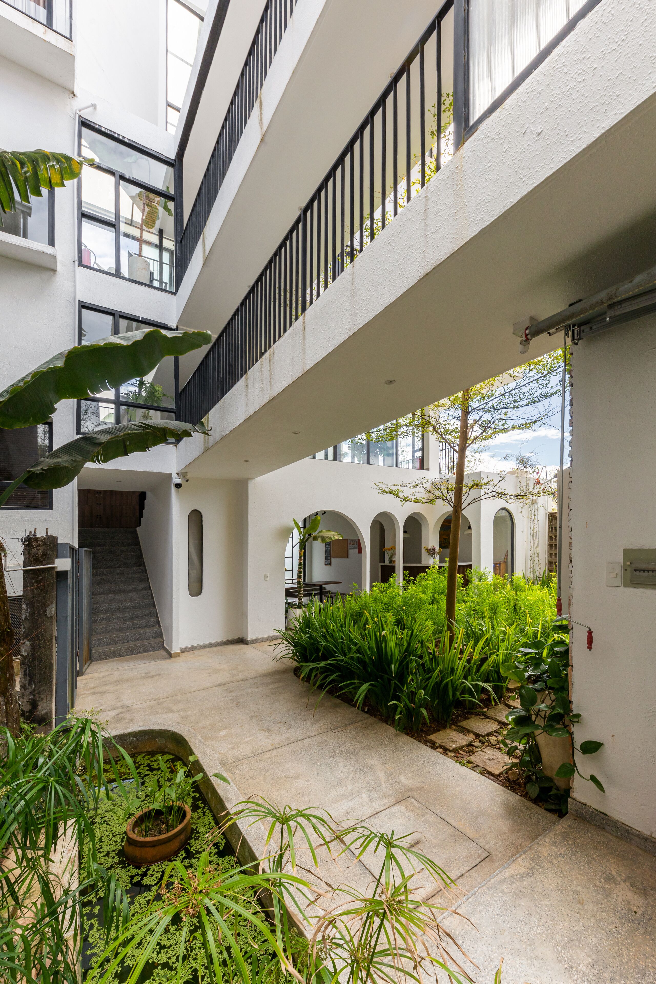 Un edificio de varios niveles con un patio central con plantas y una escalera.