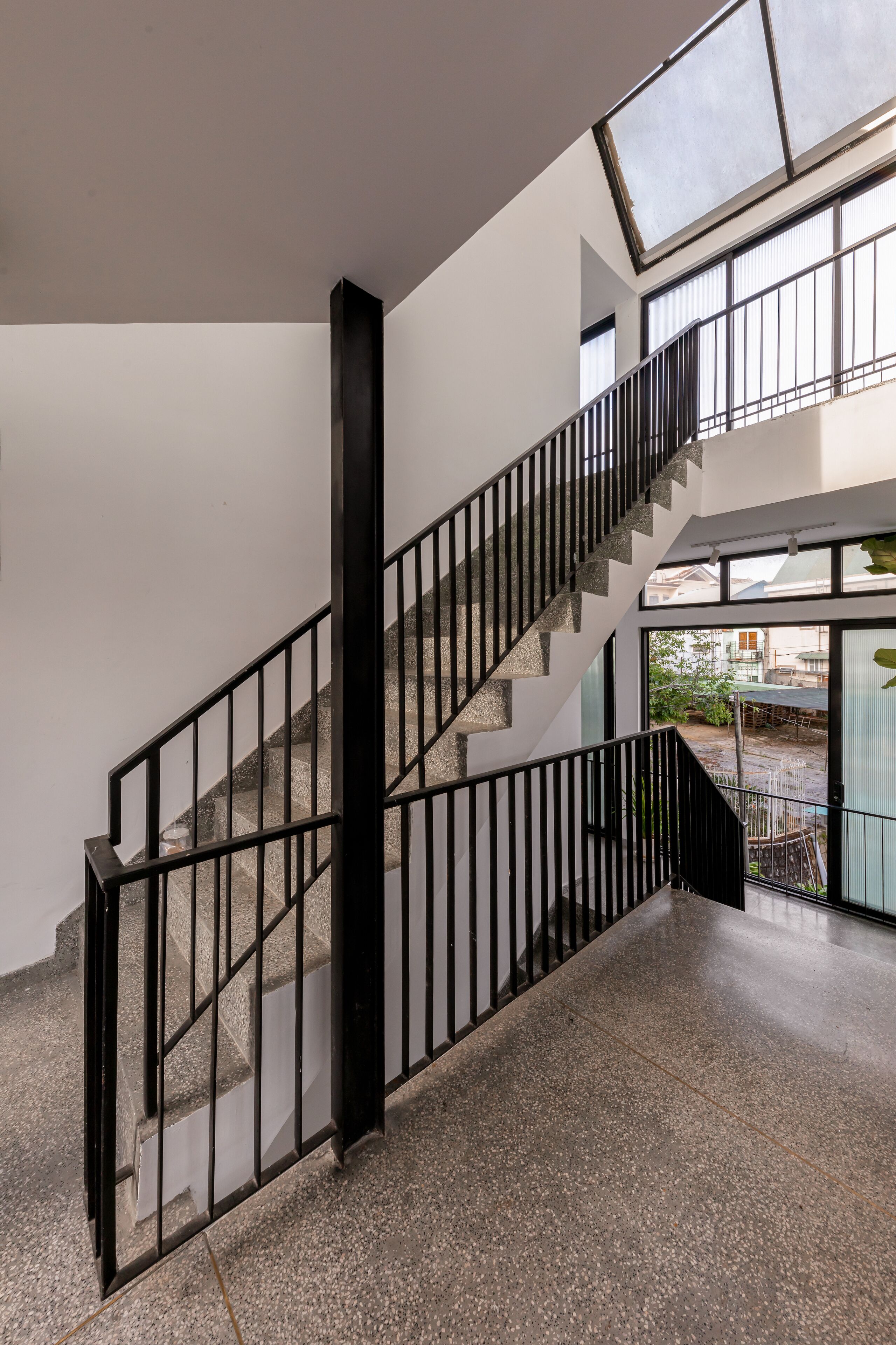 Una escalera con barandillas negras y un vidrio al final que da al exterior.