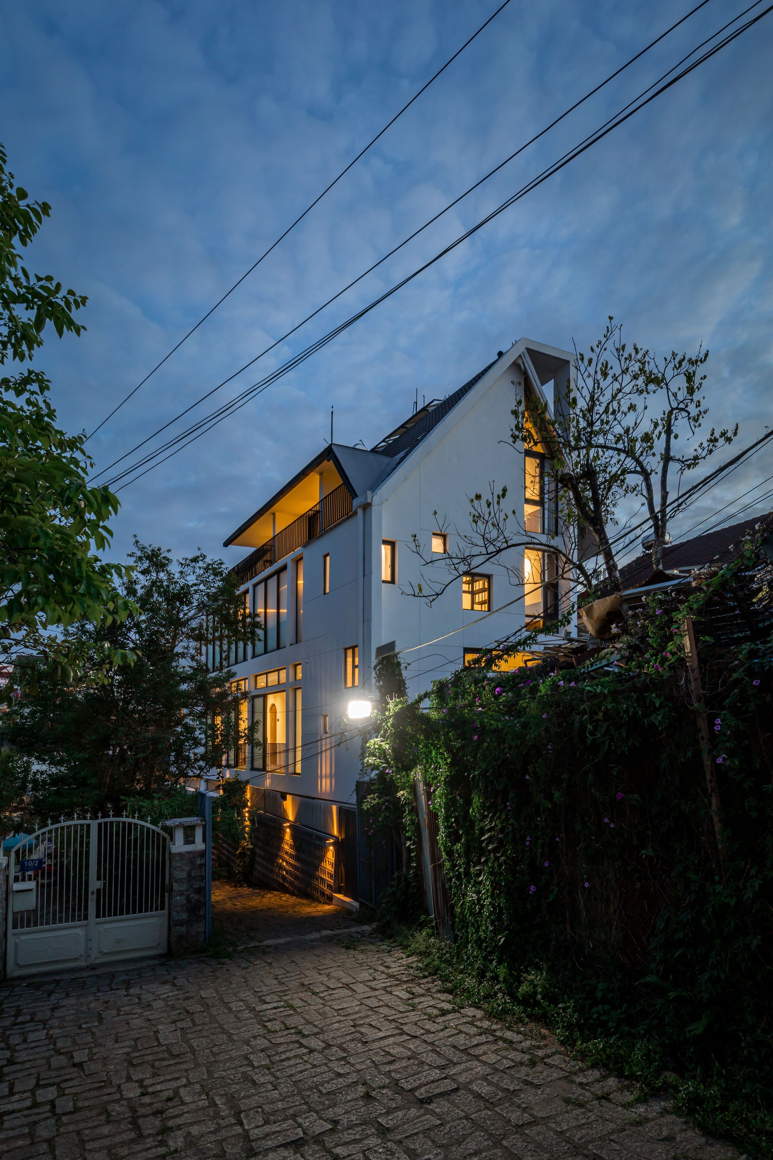 A modern two-story house with a paved driveway and a gated entrance.