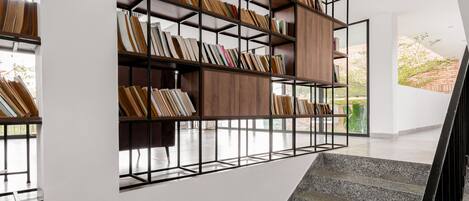 A modern interior with a staircase, a built-in bookshelf, and a view of the outdoors.