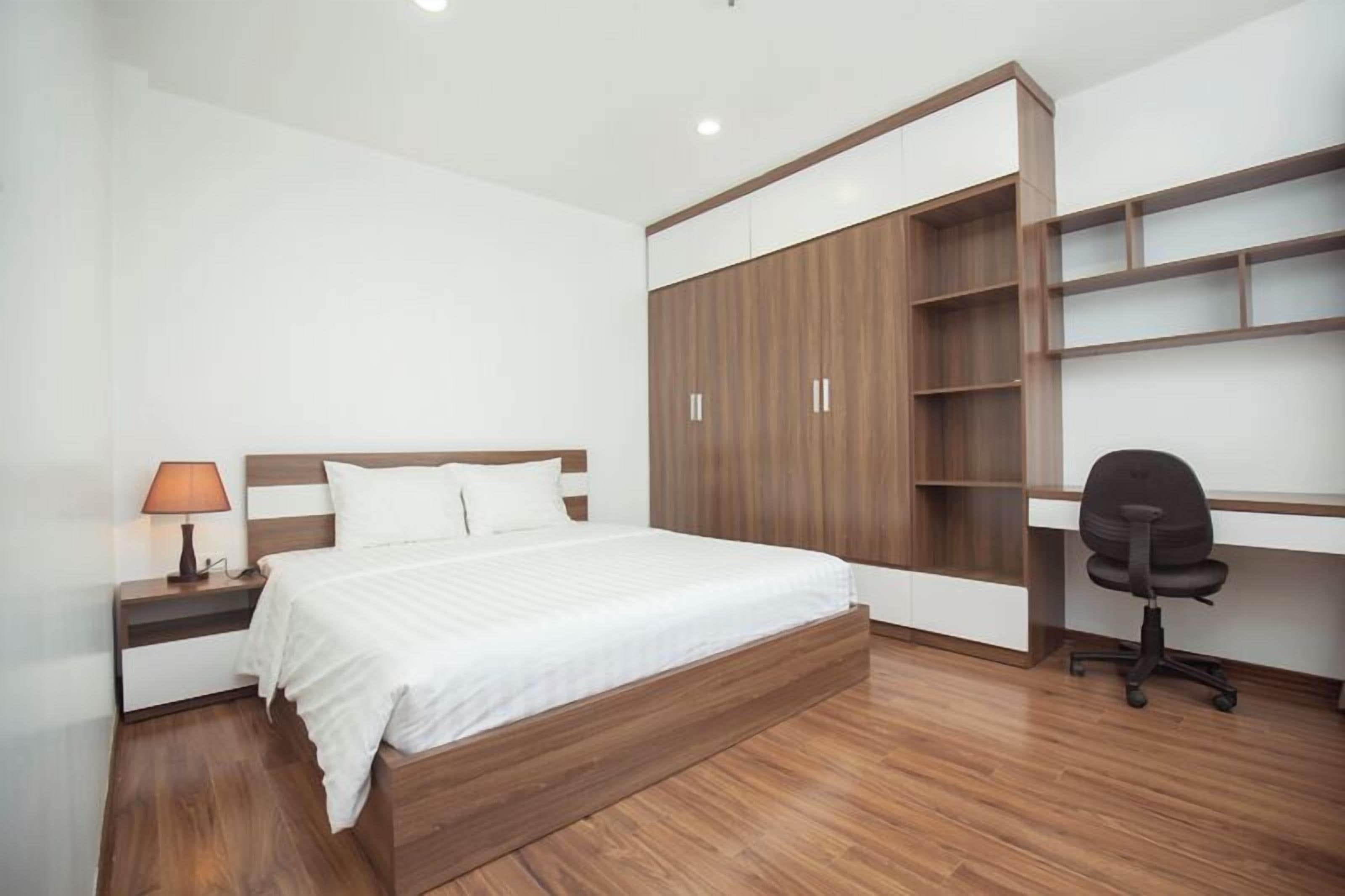 A bedroom with a bed, a nightstand, a desk, and a chair.