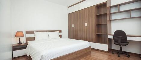 A bedroom with a bed, a nightstand, a desk, and a chair.