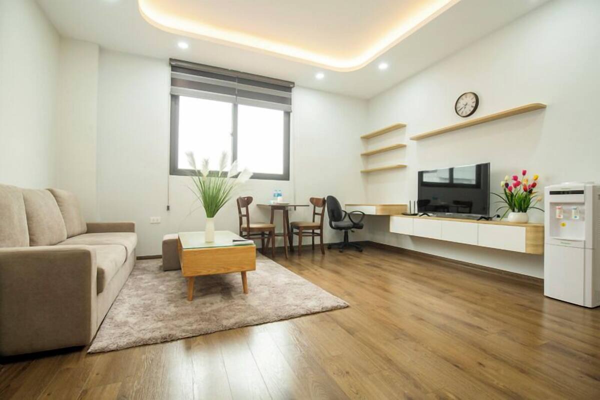 A modern living room with a sofa, coffee table, and a TV on a white cabinet.