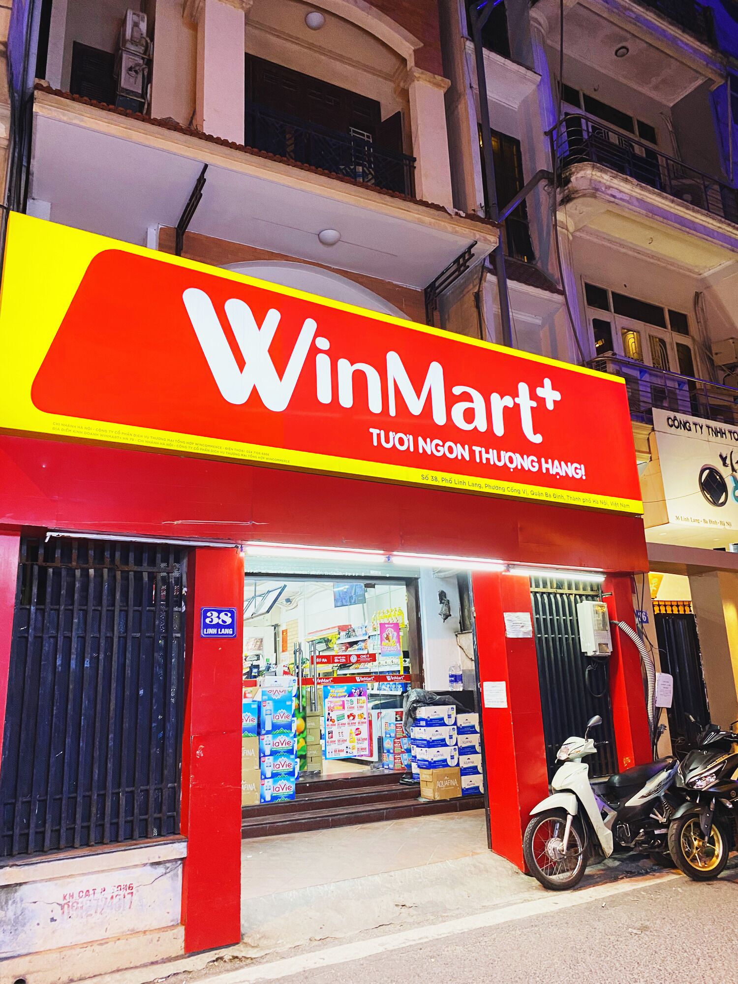 A WinMart+ store with a red and yellow sign, a motorcycle parked outside, and a visible entrance.