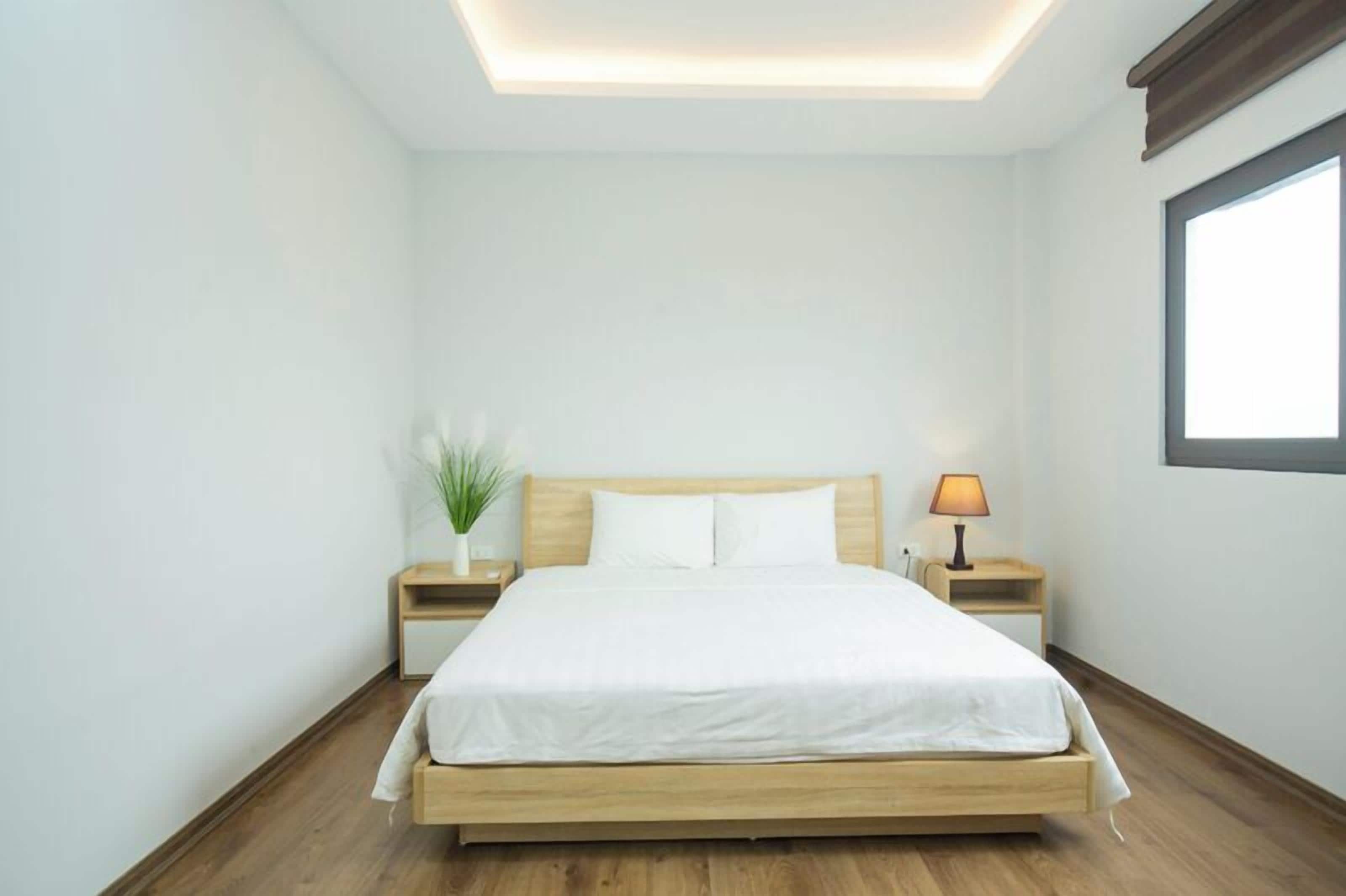 Une chambre à coucher moderne avec un lit en bois, une table de chevet avec une lampe et une petite plante en pot.