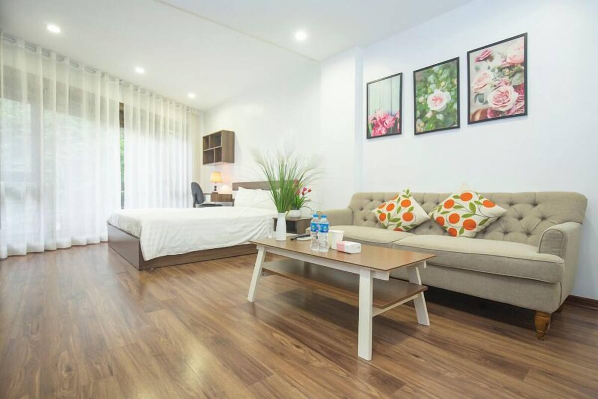 A hotel room with a bed, a sofa, a coffee table, and a potted plant.