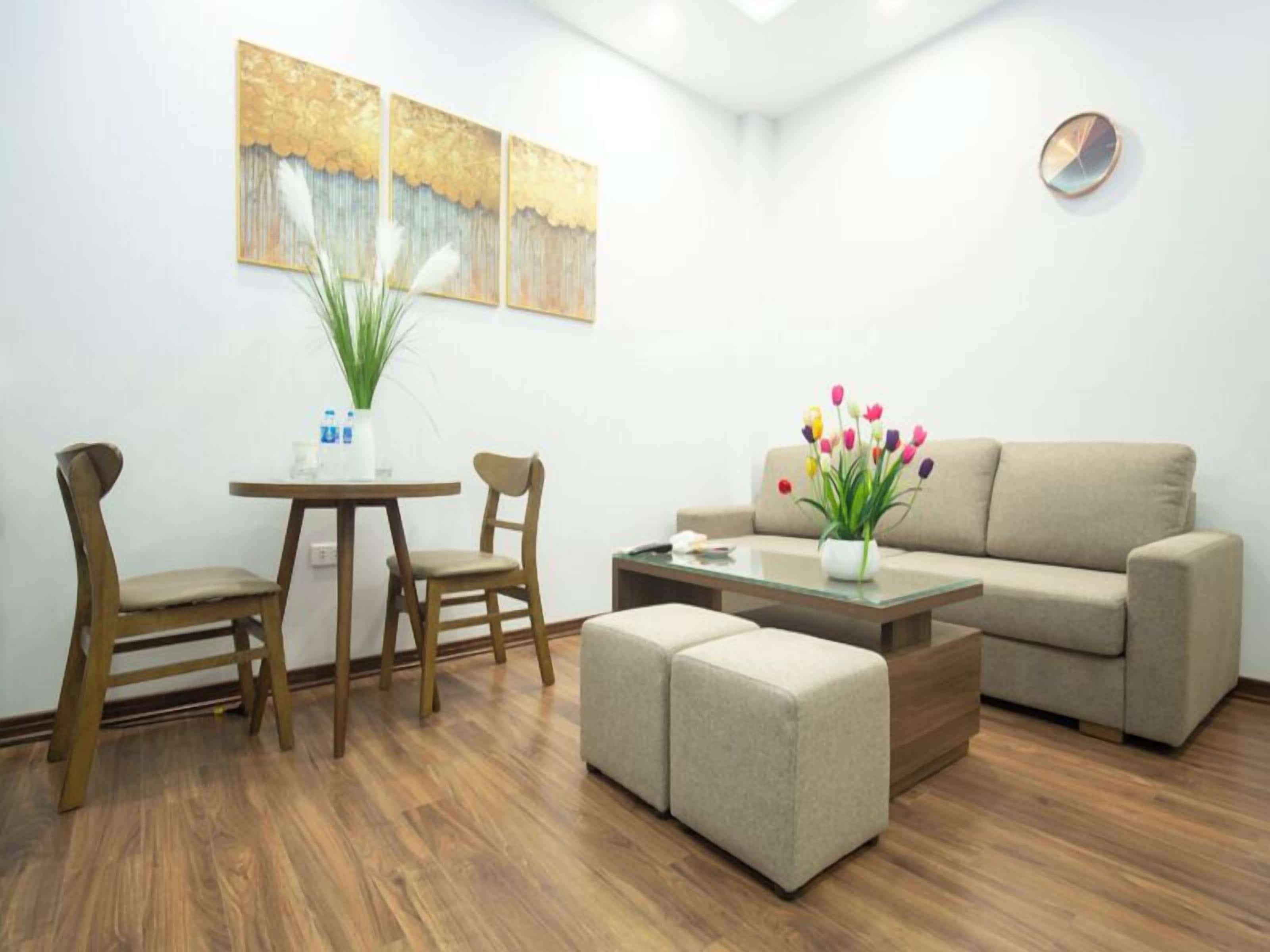 A modern living room with a sofa, two chairs, a coffee table, and a plant.
