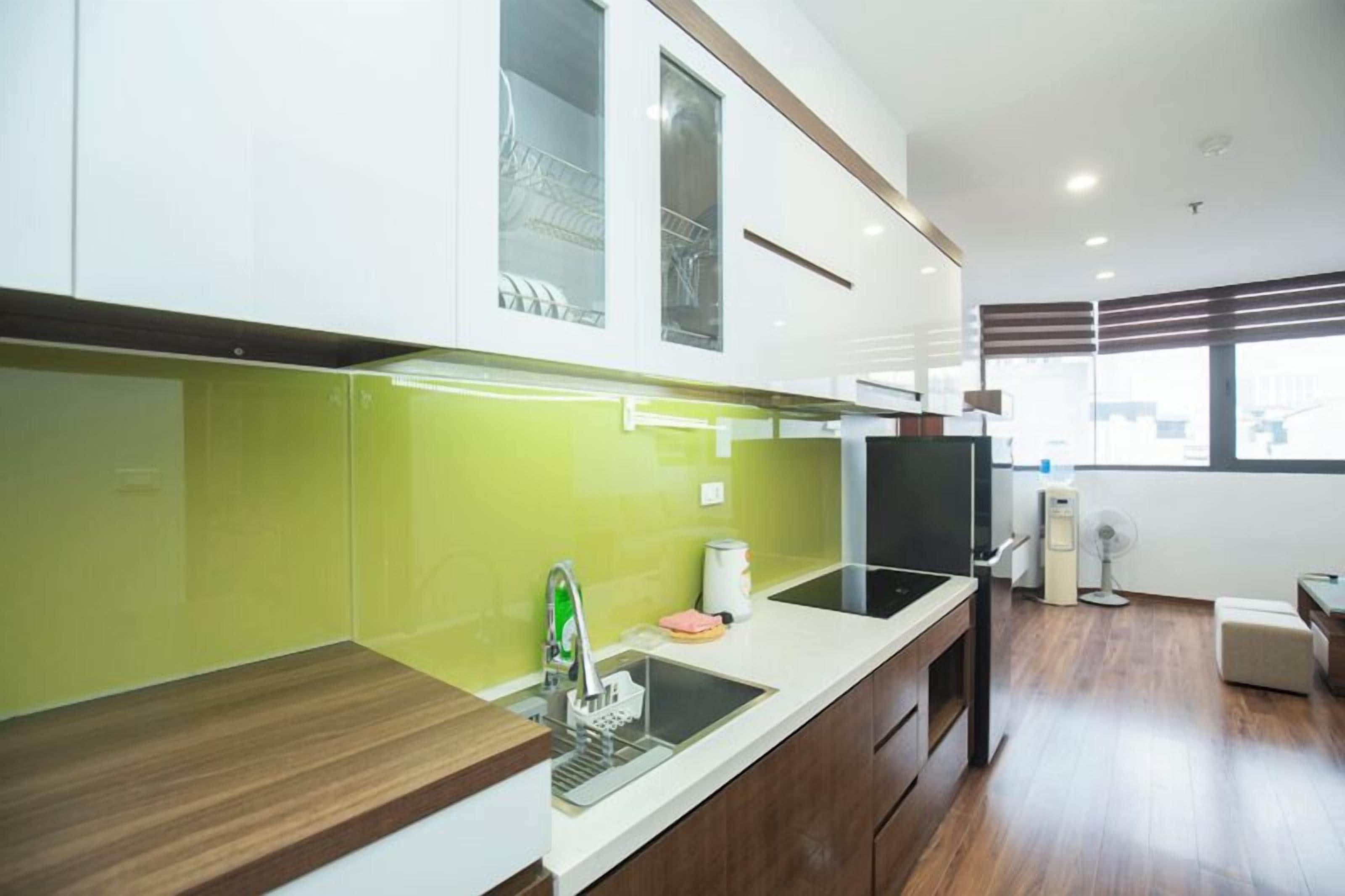 A modern kitchen with a green backsplash, white cabinets, and a wooden countertop.