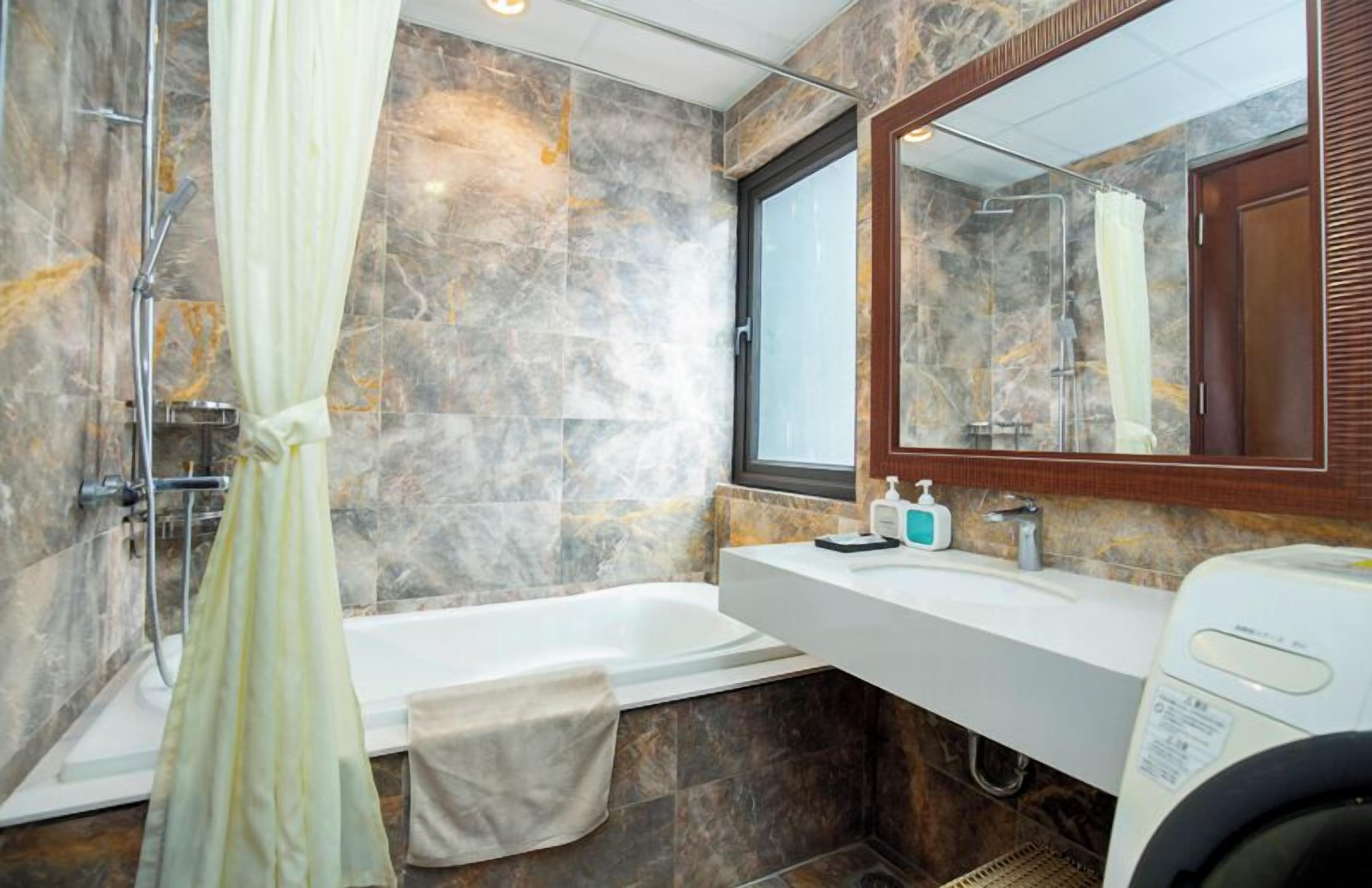 A bathroom with a bathtub, a shower, a sink, and a mirror.