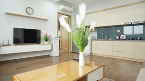 A modern living room with a flat-screen TV, a coffee machine, and a dining area with a glass table.