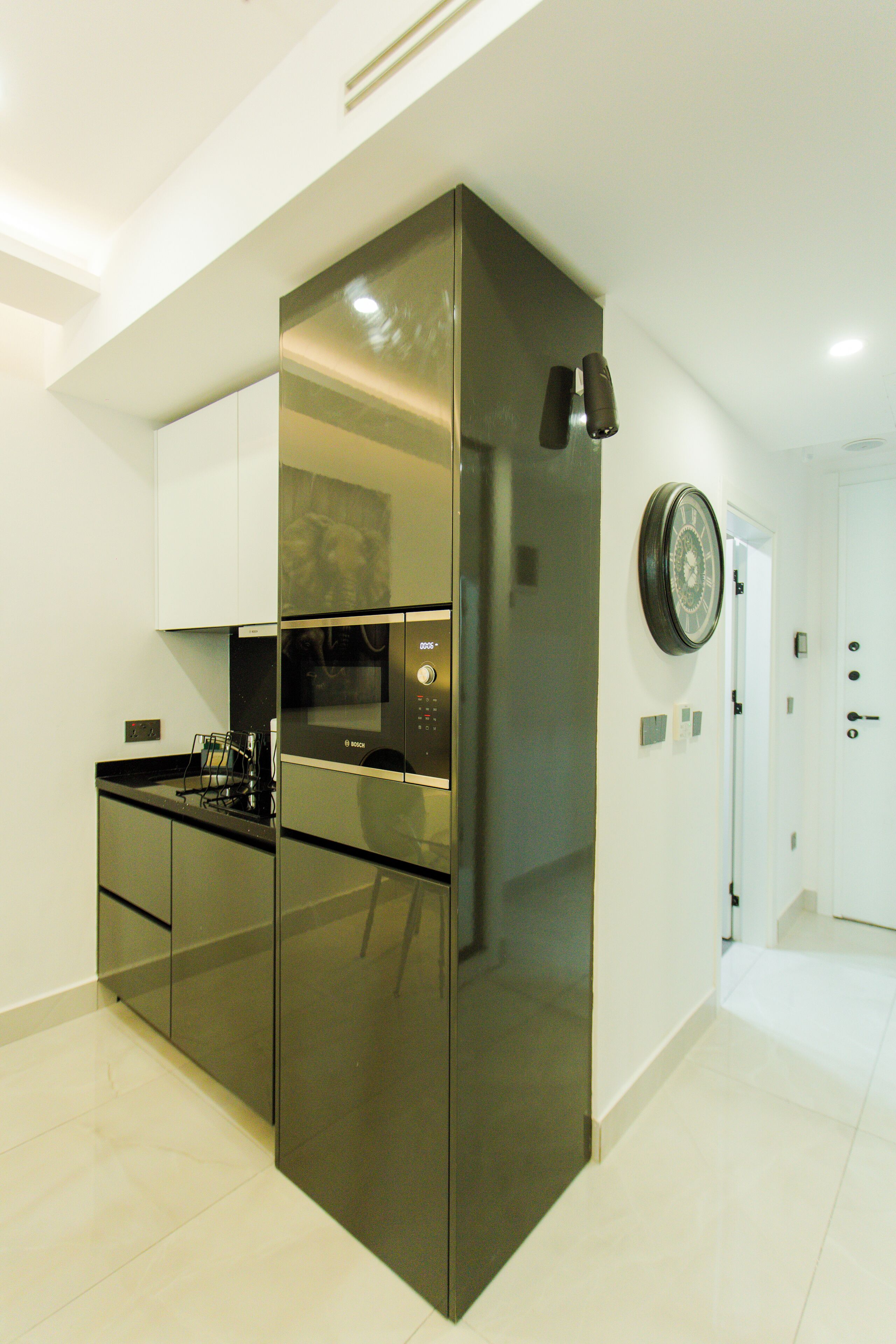 A modern kitchen with stainless steel appliances, white cabinetry, and a wall clock.