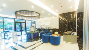 A modern lobby with a reception desk, seating area, and a large window offering a view of the outside. - Accra Luxury Apartments at Kass (Accra)