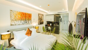 A modern hotel room with a large bed, a desk, a chair, and a small kitchenette. - Accra Luxury Apartments at Kass (Accra)