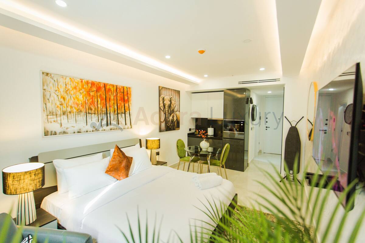Une chambre d’hôtel moderne équipée d’un grand lit, d’un bureau, d’une chaise et d’une petite kitchenette.