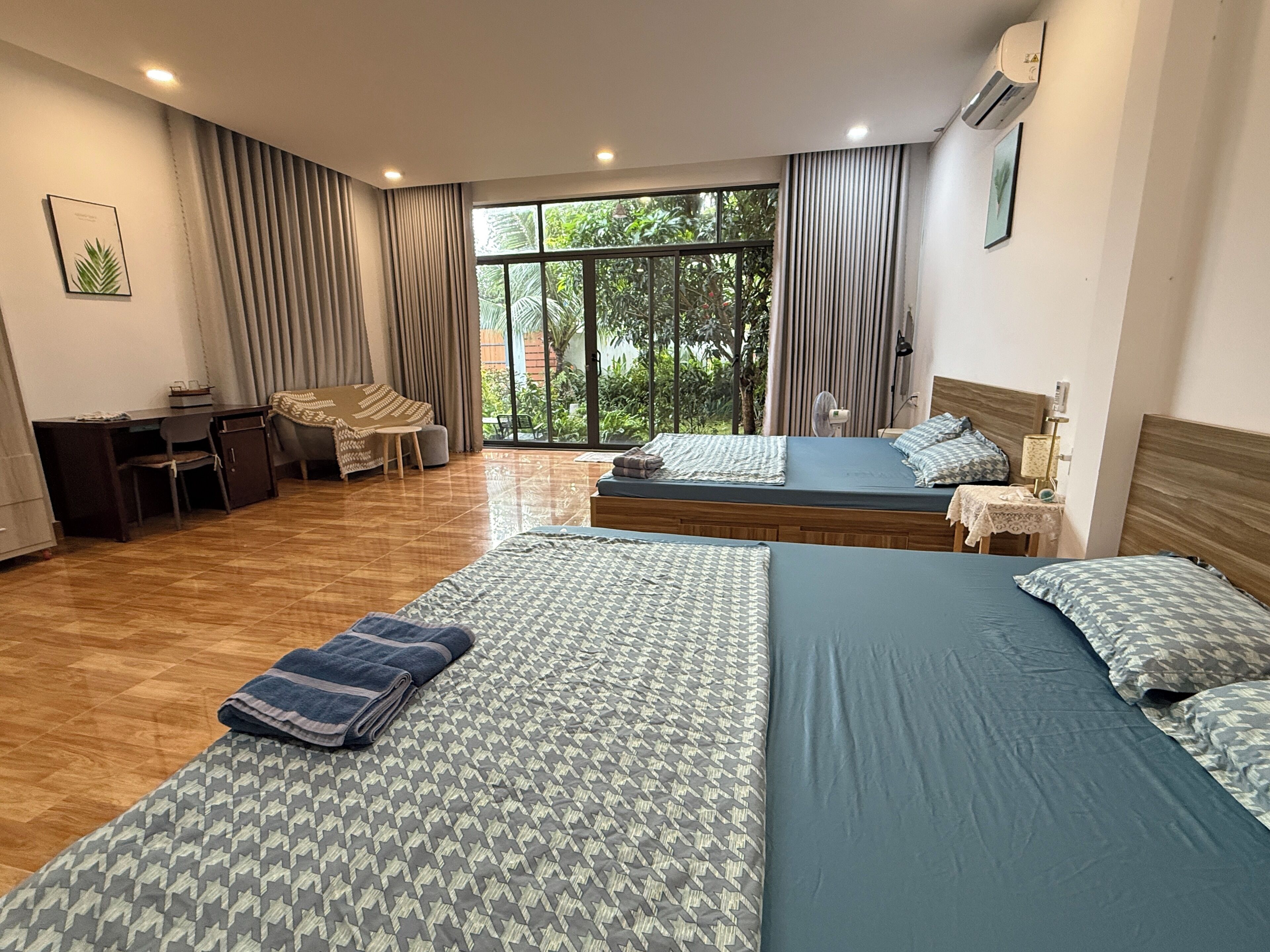A hotel room with two beds, a desk, a chair, and a large window.