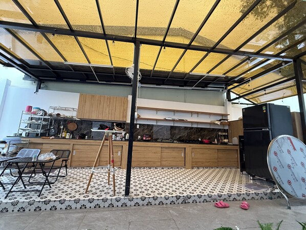 A kitchen with a tiled floor, wooden cabinets, a black refrigerator, and a dining area with a table and chairs.