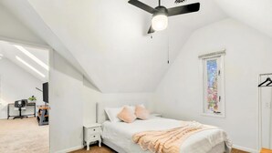 A bedroom with a bed, a ceiling fan, a nightstand, a window, and a door leading to another room. - Charming 1 BR Atlanta Retreat: Minutes to Midtown (Atlanta)