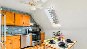 A kitchen with wooden cabinets, a dishwasher, and a dining area with a table set for four. - Charming 1 BR Atlanta Retreat: Minutes to Midtown (Atlanta)