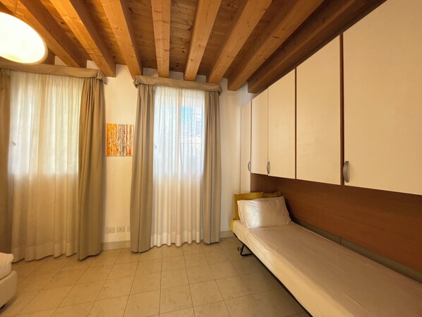 A room with a bed, a wardrobe, and a window with curtains.