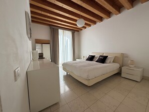 A bedroom with a bed, bedside tables, a desk, and a window with curtains.