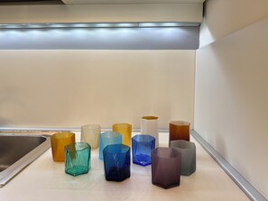 A kitchen counter with various glass vases in different shapes and sizes.