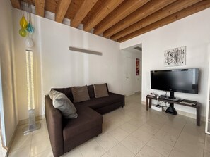 A modern living room with a brown sofa, a flat-screen TV, and a wooden ceiling.
