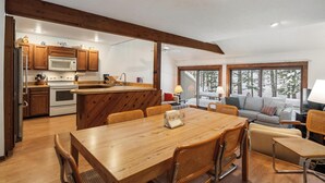 Una cocina moderna con armarios de madera, una isla central y un comedor con mesa y sillas de madera.