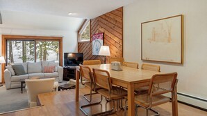 Una sala de estar moderna con una mesa de comedor de madera, sillas de mimbre, un sofá y una televisión.