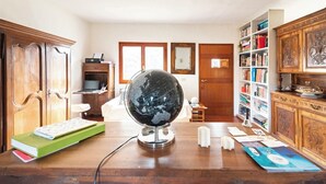 Een studeerkamer met een houten bureau, een wereldbol, boeken en een boekenkast.