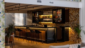 A bar area with a counter, stools, and shelves of bottles. - Le Grove Hotel (Jounieh)