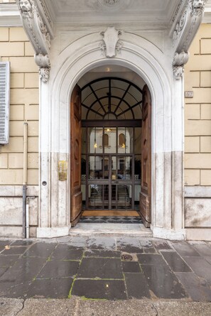 Une entrée somptueuse, avec une grande porte en arc de cercle, un sol carrelé et un mur en briques.