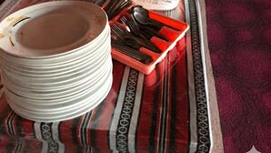 Una mesa con una variedad de platos y utensilios para un bufé, rodeada de paredes a rayas y una alfombra estampada.