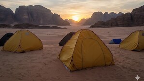 Un campamento en el desierto con tiendas de campaña y formaciones rocosas al fondo.