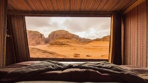 Una habitación con cama y un amplio ventanal que ofrece vistas a un paisaje desértico.